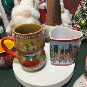 Two Christmas mugs. One Gingerbread man with a red handle and heart shaped .